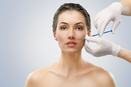 Woman with injection being made into her face with two gloved hands