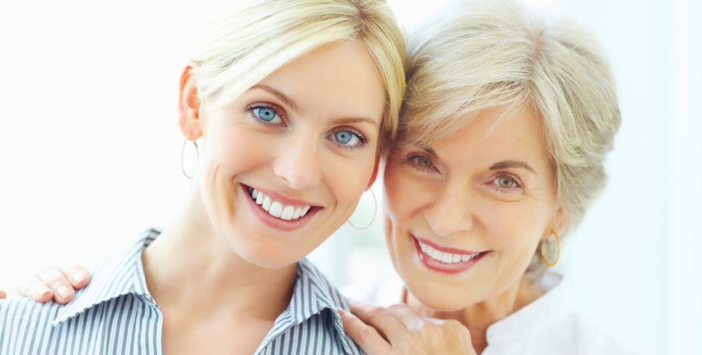 An older woman places her hands on a younger woman's shoulders.