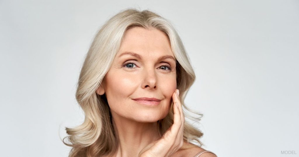 A mature woman with blonde hair with her hand touching her face. (Model)